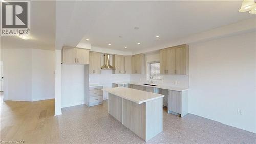 Modern kitchen featuring light wood-finish cabinetry, a large center island with a light-toned countertop, and a stainless steel range hood - 200 Cittadella Boulevard, Hamilton, ON 