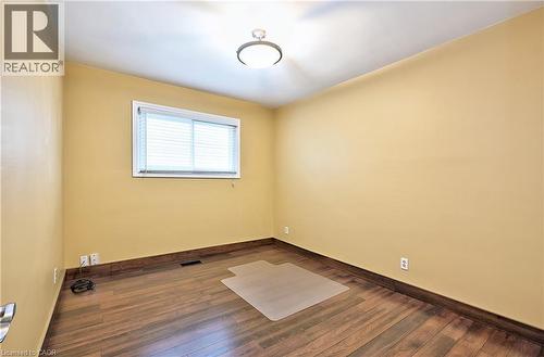 Room featuring wood-finish flooring, a window with horizontal blinds, and a flush-mount ceiling light fixture - 1476 Barton Street E Unit# 2, Hamilton, ON 