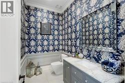 Powder room featuring striking blue and white patterned wallpaper with wainscoting trim - 