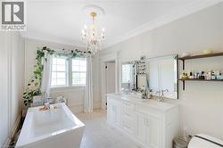 Bright bathroom featuring a freestanding tub, double vanity with integrated sinks, and a crystal chandelier - 
