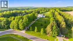 Expansive property featuring a white two-story residence, a long paved driveway, and mature landscaping - 