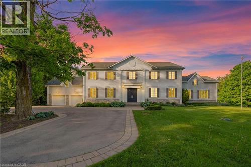 Two-story residence featuring light-colored siding, a dark entry door, and multiple windows with dark shutters - 6195 Milburough Line, Burlington, ON - Outdoor With Facade
