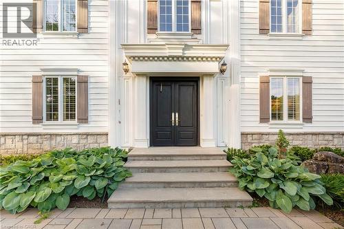 White clapboard exterior featuring a double entry door, decorative door surround, wall sconces, and functional shutters - 6195 Milburough Line, Burlington, ON - Outdoor