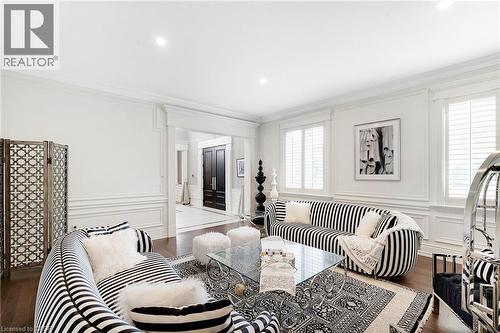 Spacious living area featuring wood-finish flooring, white paneling, and crown molding - 6195 Milburough Line, Burlington, ON - Indoor