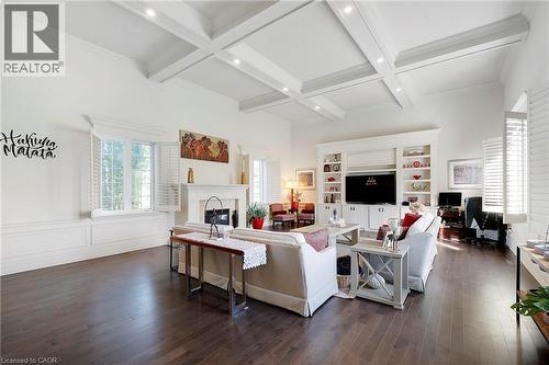 Living area featuring coffered ceilings with recessed lighting, wood-finish flooring, a fireplace with a white mantel, and built-in cabinetry - 6195 Milburough Line, Burlington, ON - Indoor Photo Showing Living Room With Fireplace
