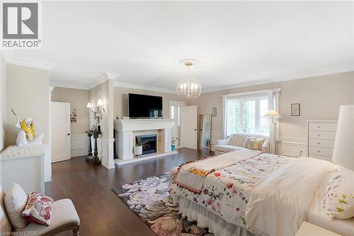 Spacious room featuring dark wood-finish flooring and a white crown molding - 6195 Milburough Line, Burlington, ON - Indoor Photo Showing Bedroom With Fireplace