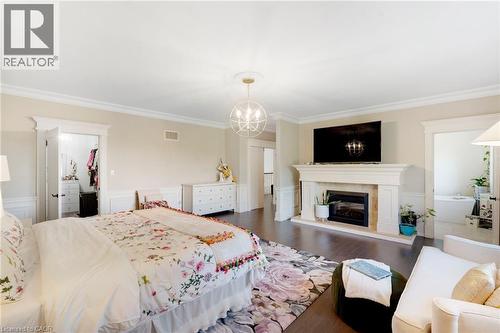 Spacious room featuring dark wood-finish flooring, a traditional fireplace with a stone mantel, crown molding, and wainscoting - 6195 Milburough Line, Burlington, ON - Indoor Photo Showing Bedroom With Fireplace