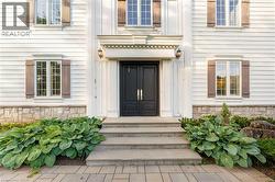 White clapboard exterior featuring a double entry door, decorative door surround, wall sconces, and functional shutters - 