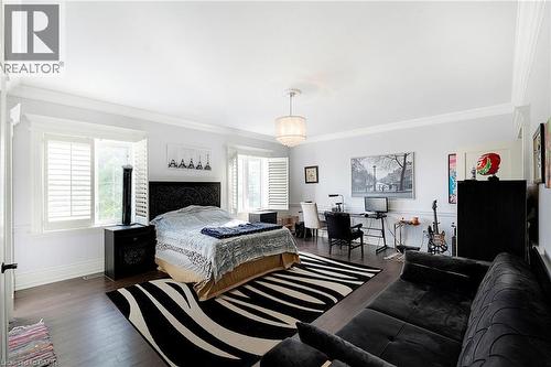 Spacious room featuring dark wood-finish flooring, multiple windows with white plantation shutters, and extensive white crown molding - 6195 Milburough Line, Burlington, ON - Indoor Photo Showing Bedroom