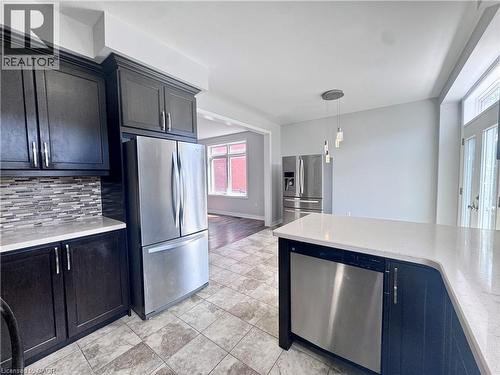 Kitchen featuring dark cabinetry, stainless steel appliances, mosaic tile backsplash, and light-toned countertops - 154 Rosemount Drive, Kitchener, ON 