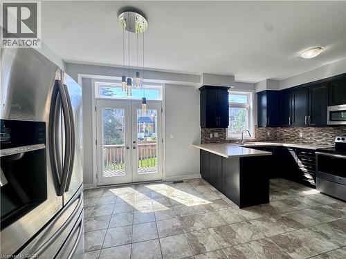 Kitchen featuring dark cabinetry, light countertops, and a mosaic tile backsplash - 154 Rosemount Drive, Kitchener, ON 