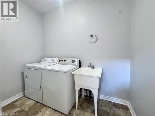 Dedicated laundry area featuring white appliances, a utility sink with a chrome faucet, and tiled flooring - 154 Rosemount Drive, Kitchener, ON 