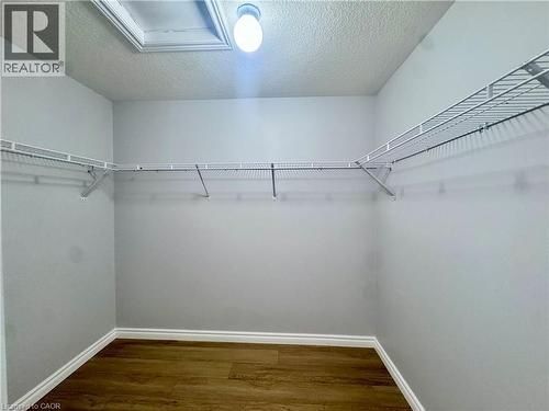Storage area featuring wood-finish flooring, white wire shelving, a ceiling-mounted light fixture, and white baseboard trim - 154 Rosemount Drive, Kitchener, ON 