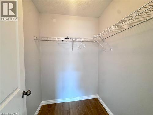Walk-in closet featuring light gray walls, white baseboards, and wood-finish flooring - 154 Rosemount Drive, Kitchener, ON 
