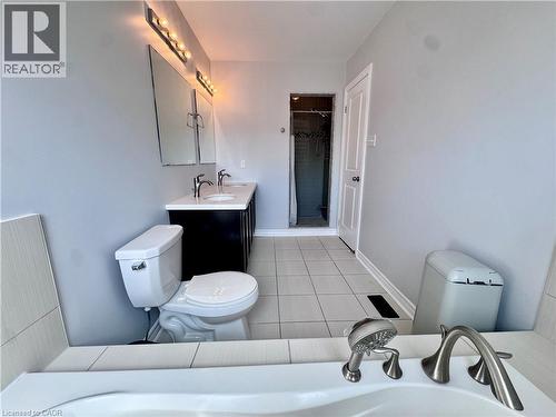 Spacious bathroom featuring a dual vanity with white countertop, chrome fixtures, tiled flooring, and a built-in shower - 154 Rosemount Drive, Kitchener, ON 