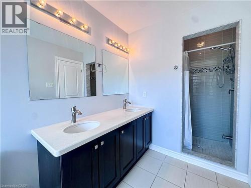 Dual vanity with a white countertop and dark cabinetry, individual mirrors, and vanity lighting - 154 Rosemount Drive, Kitchener, ON 