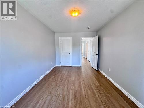 Room featuring wood-finish flooring, light grey walls, white baseboards, and white interior doors - 154 Rosemount Drive, Kitchener, ON 
