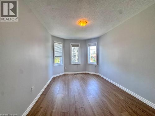 Bay window with three individual windows, wood-finish flooring, light grey wall paint, white baseboards, and a ceiling-mounted light fixture - 154 Rosemount Drive, Kitchener, ON 