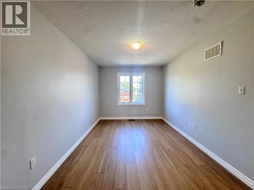 Bright room featuring wood-finish flooring, light gray walls, a white-framed window, and a ceiling-mounted light fixture - 154 Rosemount Drive, Kitchener, ON 