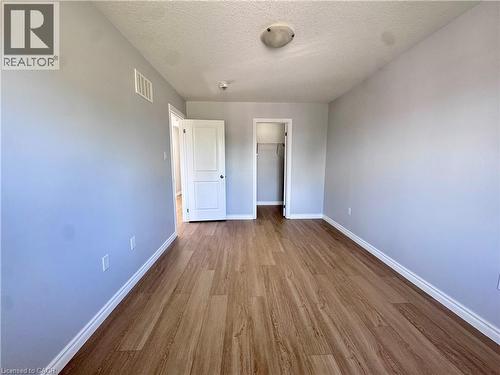 Spacious room featuring wood-finish flooring, light grey walls, and white trim - 154 Rosemount Drive, Kitchener, ON 