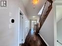 Hallway featuring wood-finish flooring, light grey walls, and a prominent wood staircase with matching railing - 154 Rosemount Drive, Kitchener, ON 