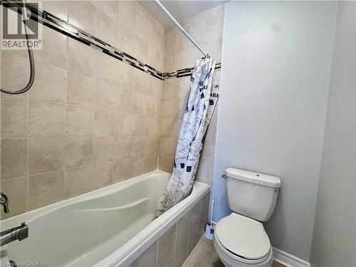 Bathtub and shower combination featuring beige ceramic wall tiles with a decorative mosaic accent band - 154 Rosemount Drive, Kitchener, ON 