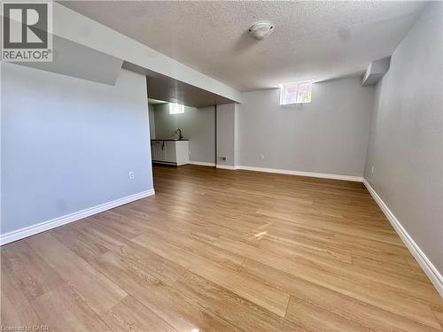 Spacious interior with wood-finish flooring, light grey painted walls, white baseboards, and a contemporary ceiling light fixture - 154 Rosemount Drive, Kitchener, ON 