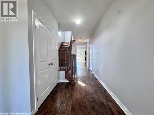 Hallway featuring dark wood-finish flooring, light grey painted walls, white trim, and a two-panel bi-fold closet door - 154 Rosemount Drive, Kitchener, ON 