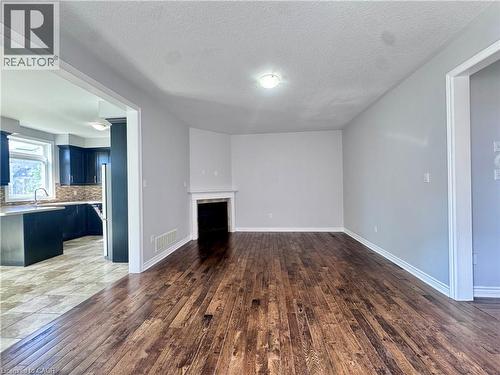 Living area featuring wood-finish flooring, a white mantelpiece, and a contemporary ceiling light fixture - 154 Rosemount Drive, Kitchener, ON 