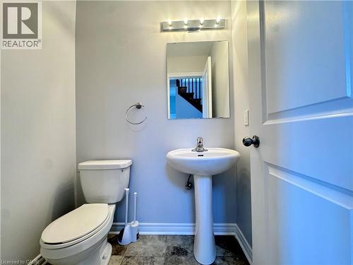 Pedestal sink with chrome faucet, wall-mounted mirror, and vanity lighting - 154 Rosemount Drive, Kitchener, ON 
