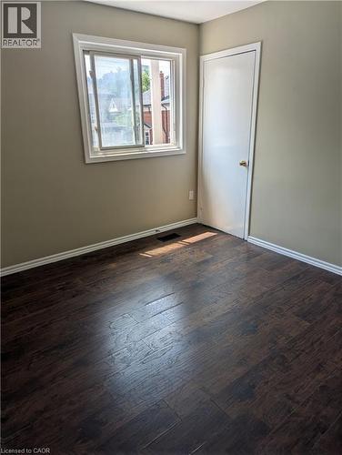 Room featuring dark wood-finish flooring, light tan walls, and white baseboards - 949 E Main Street E, Hamilton, ON 