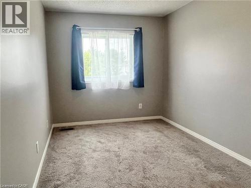 Room featuring neutral wall tones, textured carpeting, and a window with natural light - 209 Auburn Drive Unit# A, Waterloo, ON 