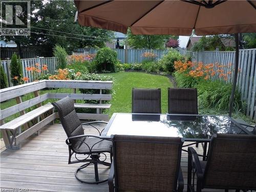 Wood-finish deck featuring a built-in bench, offering direct access to the manicured lawn and garden beds - 209 Auburn Drive Unit# A, Waterloo, ON 