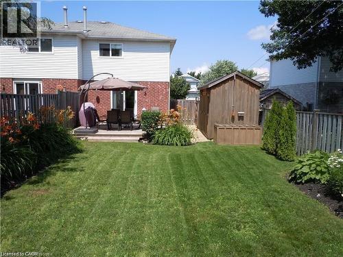 Expansive backyard featuring a lush lawn, wooden privacy fencing, and mature landscaping - 209 Auburn Drive Unit# A, Waterloo, ON 