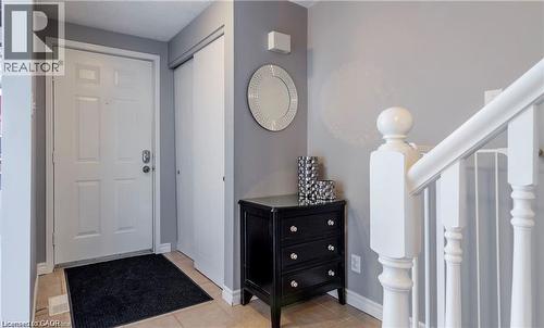 Foyer with light-toned tile flooring, a paneled entry door, and an adjacent closet with white sliding doors - 209 Auburn Drive Unit# A, Waterloo, ON 