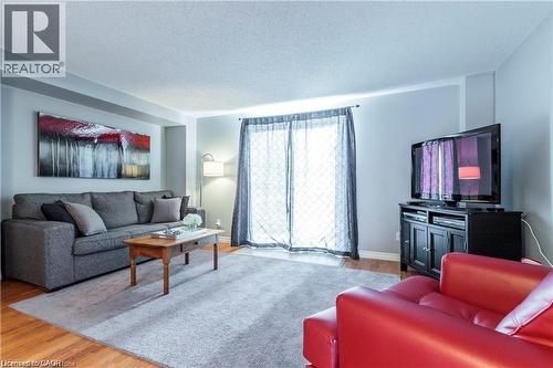 Living area featuring wood-finish flooring, light grey walls, and a recessed ceiling element - 209 Auburn Drive Unit# A, Waterloo, ON 