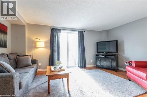Living area featuring wood-finish flooring, light grey painted walls, and a white ceiling - 209 Auburn Drive Unit# A, Waterloo, ON 