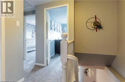Carpeted hallway featuring light gray walls, white trim, and white painted balusters - 209 Auburn Drive Unit# A, Waterloo, ON 