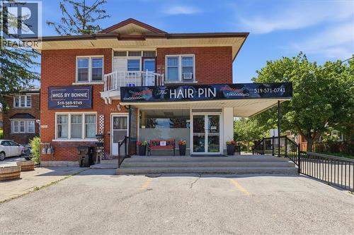 Two-story brick building featuring a ground-level commercial storefront with an awning, large display windows, and a double-door entry - 744 Queen Street S, Kitchener, ON 
