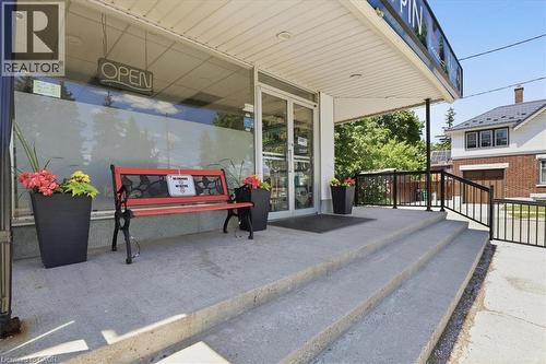 Commercial storefront featuring a wide concrete entrance, large display windows, and a covered porch area - 744 Queen Street S, Kitchener, ON 