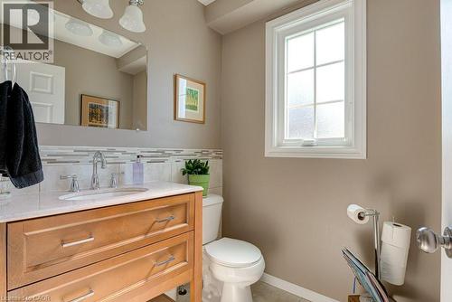 Bathroom featuring a wood-finish vanity with a light-toned countertop, a tile backsplash, and a window with privacy glass - 61 Ditner Avenue, Baden, ON - Indoor Photo Showing Bathroom