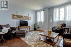 Living area featuring wood-finish flooring, light grey walls, white trim, and recessed lighting - 