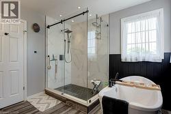 Glass-enclosed shower with subway tile surround, hexagon tile flooring, and a matte black rainfall showerhead - 