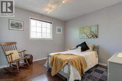 Bedroom featuring wood-finish flooring, light gray walls, and a window with white blinds - 