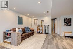 Spacious living area featuring light gray walls, recessed ceiling lighting, wood-finish flooring, and a large area rug - 