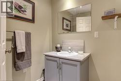 Powder room featuring a single vanity with a white basin and light-toned countertop, complemented by a rectangular wall-mounted mirror - 
