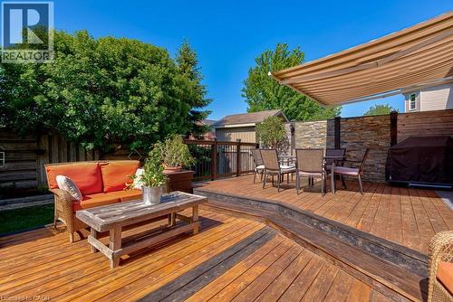 Multi-level wood deck featuring a retractable awning, stacked stone accent wall, and perimeter privacy fencing - 61 Ditner Avenue, Baden, ON - Outdoor With Deck Patio Veranda With Exterior