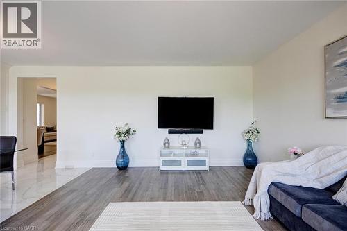 Expansive living space featuring wood-finish flooring, a wall-mounted television, and neutral wall tones - 57 Hollybrook Trail, Kitchener, ON 