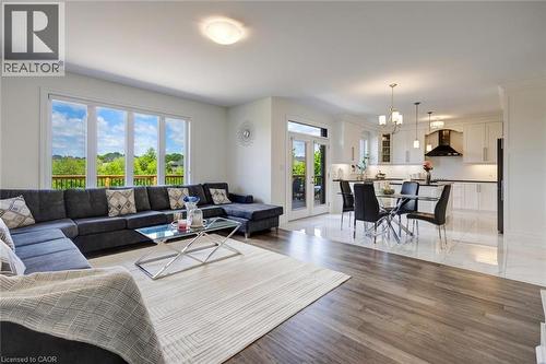 Open-concept living area featuring wood-finish flooring, large windows, and a glass-paneled door - 57 Hollybrook Trail, Kitchener, ON 