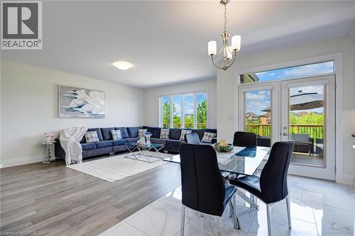 Open-concept living and dining area featuring wood-finish flooring in the living space and polished tile in the dining area - 57 Hollybrook Trail, Kitchener, ON 